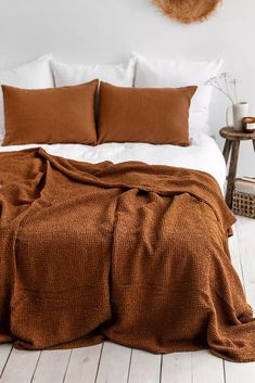 a bed with brown blankets and pillows on top of it in a white walled room