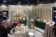 a group of people standing around a table with flowers and candles on it at an event