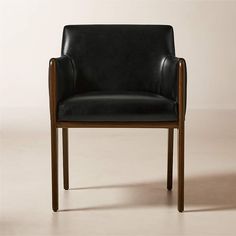 a black leather chair sitting on top of a white floor next to a wooden frame