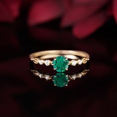 an emerald and diamond ring on a red rose