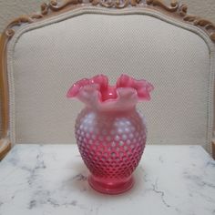 a pink vase sitting on top of a white table