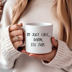 a woman holding a coffee mug with the words i'm just like, damn, it's 7am