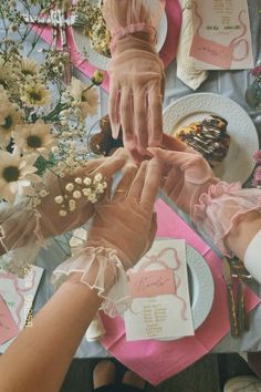 two hands reaching for each other at a table with flowers and napkins on it