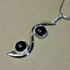 I fabricated this Sterling Silver Pendant to swirl around the two 10 mm round Black Onyx cabochon's.  The curved flowing silver gives motion to the piece.  It is 2-5/8 inches long × 3/4  inches wide. A very fun, yet elegant piece. I am including a Sterling Silver 18 inch long 8 sided Snake Chain so it can be worn immediately. Silver Round Elegant Cabochons, Elegant Silver Round Cabochons, Silver Round Cabochons For Formal Use, Round Silver Cabochons For Formal Use, Elegant Black Spiral Jewelry, Unique Black Spiral Jewelry, Nickel-free Black Spiral Jewelry, Silver Round Cabochons With Polished Finish, Black Obsidian Stone