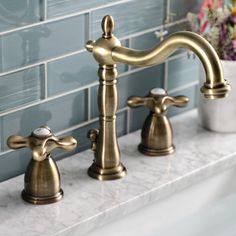 two brass faucets on a marble counter top