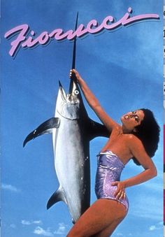 a woman in a purple bathing suit holding onto a dolphin on a blue sky background