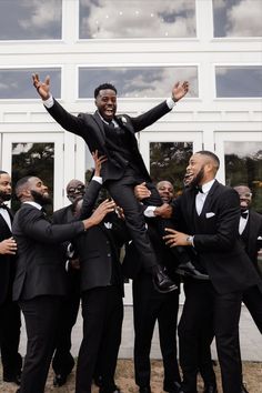 a group of men in tuxedos standing around each other with their arms up