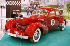 an old red car is on display in a showroom