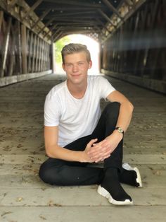 a young man sitting on the ground in front of a tunnel with his legs crossed