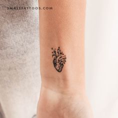 a small tattoo on the wrist of a woman's arm with a heart and flowers