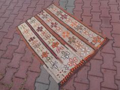 an old rug is laying on the ground in front of a brick sidewalk with cobblestones