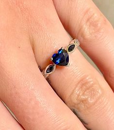 a woman's hand with a blue ring on top of her finger and a diamond in the middle