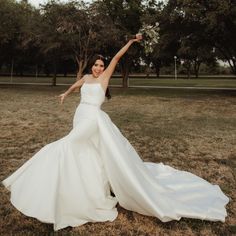 a woman in a white wedding dress is holding her arms up and posing for the camera