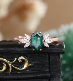 a close up of a ring with an emerald colored stone and diamond accents on it