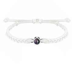 a white leather cord bracelet with a black bead on the clasp and a silver ball