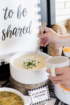 two people are serving soup to each other at a table with signs and bowls on it