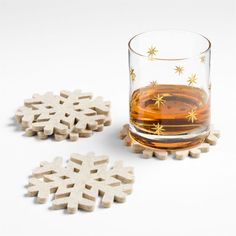 a shot glass filled with liquid and wooden snowflake coasters on a white surface