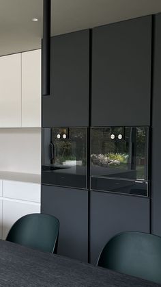 two black cats are seen through the windows in this modern kitchen area with white cabinets and gray countertops