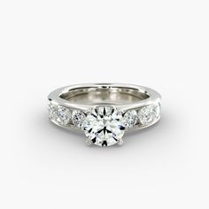 a white gold engagement ring with three stones on the side and a channeled band