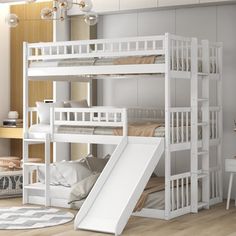 there is a white bunk bed with a slide in the middle and a rug on the floor