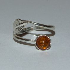 Amber and silver adjustable leaf ring Boho 925 stamped sterling silver adjustable leaf ring featuring a round Amber gemstone.     * Round Amber cabochon 6mm     * 925 Sterling silver     * Size: N - Adjustable Made from fossilised tree resin, amber is one of the lightest and softest organics with a rating of between 2 and 3 on the gemstone hardness scale. Sensitive to heat, sunlight and chemicals including perfume and hairspray, your Amber ring should be removed before taking a shower. To care f Nature-inspired Sterling Silver Cabochon Ring, Adjustable Amber Open Ring, Silver Leaf-shaped Ring As Gift, Silver Leaf Ring Gift, Silver Leaf Ring As Gift, Adjustable Amber Cabochon Rings, Adjustable Sterling Silver Ring With Amber Color, Adjustable Sterling Silver Amber Ring, Adjustable Sterling Silver Rings In Amber