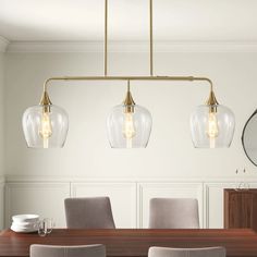 a dining room table with four lights hanging over it