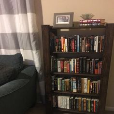 a bookshelf filled with lots of books next to a couch