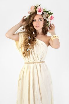 a beautiful young woman in a white dress with flowers on her head posing for the camera