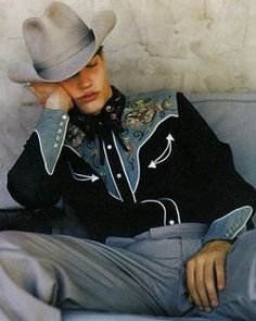 a man sitting on top of a couch wearing a cowboy hat