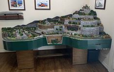 a model train set sitting on top of a table in a room with pictures above it