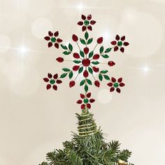 a christmas tree decorated with red flowers and green leaves in the shape of a snowflake