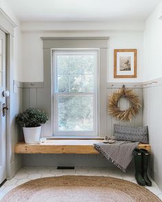 a room with a window, rug and potted plants on the windows sill