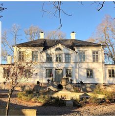 a large white house sitting in the middle of a forest