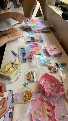 the table is covered with lots of crafting supplies, including beads and bracelets