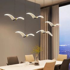 a dining room table with chairs and lights hanging from it's ceiling above the table