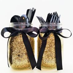 two mason jars with utensils and spoons in them are decorated with black ribbon