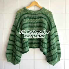 a green sweater hanging on a white tile wall with the words fire sweater written across it