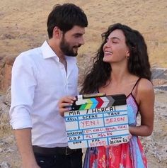 a man and woman standing next to each other with a sign on the side of them