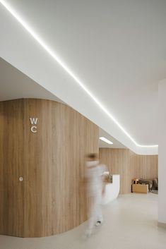 a blurry photo of a person walking in an office building with wood walls and white floors