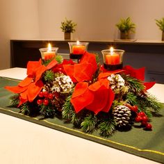 some candles are sitting on a table with christmas decorations