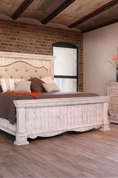 a large white bed sitting inside of a bedroom next to a wooden dresser and mirror