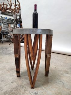 a wine bottle sitting on top of a wooden table next to a metal vase and some branches