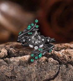 a ring with green stones and leaves on it sitting on top of a wooden surface