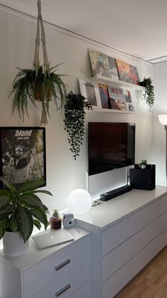 a living room with white furniture and plants on the wall above it's tv