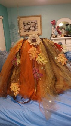 an orange tulle with flowers and leaves on it sitting on top of a bed