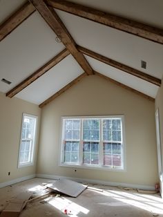 an empty room with two windows and some wood beams on the ceiling is being remodeled