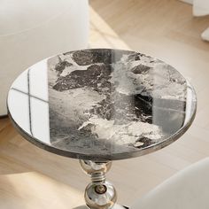 a marble topped table sitting on top of a wooden floor next to a white chair