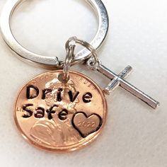 a penny keychain with the words drive safe on it and a cross in the middle