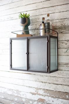 a wall mounted shelf with a glass door on it and bottles sitting on top of it