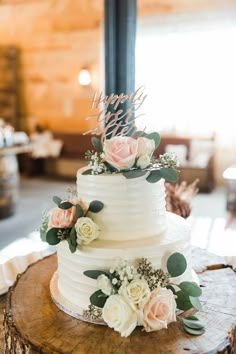 a wedding cake with flowers and greenery sits on top of a tree stump at the reception table